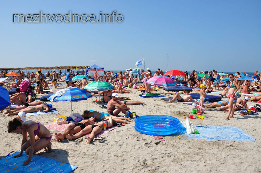 пляж наполнен отдыхающими, принимающими солнечные ванны