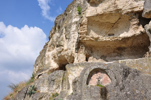 каменная стена с проделанными в ней жилищами для монахов у входа в крепость